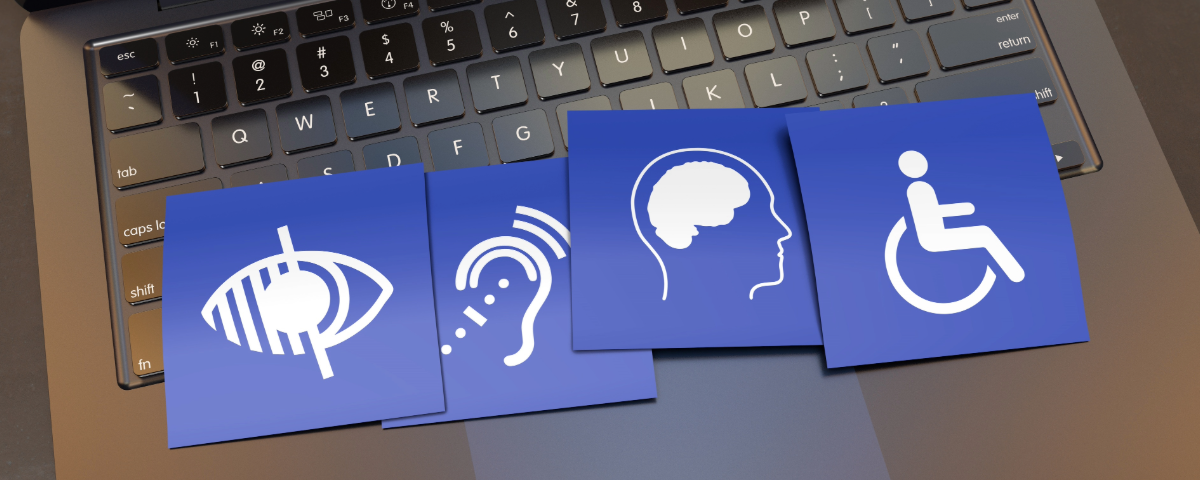 laptop with 4 cards laying across the keyboard including the icons for visual, auditory, cognitive and motor disabilities.