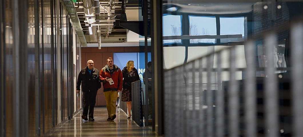 Three people walk down the hallway in Asbjornson Hall.