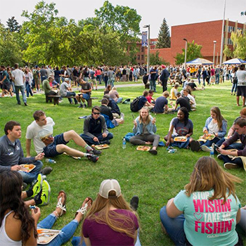 sudents sitting in the grass at an outdoor event