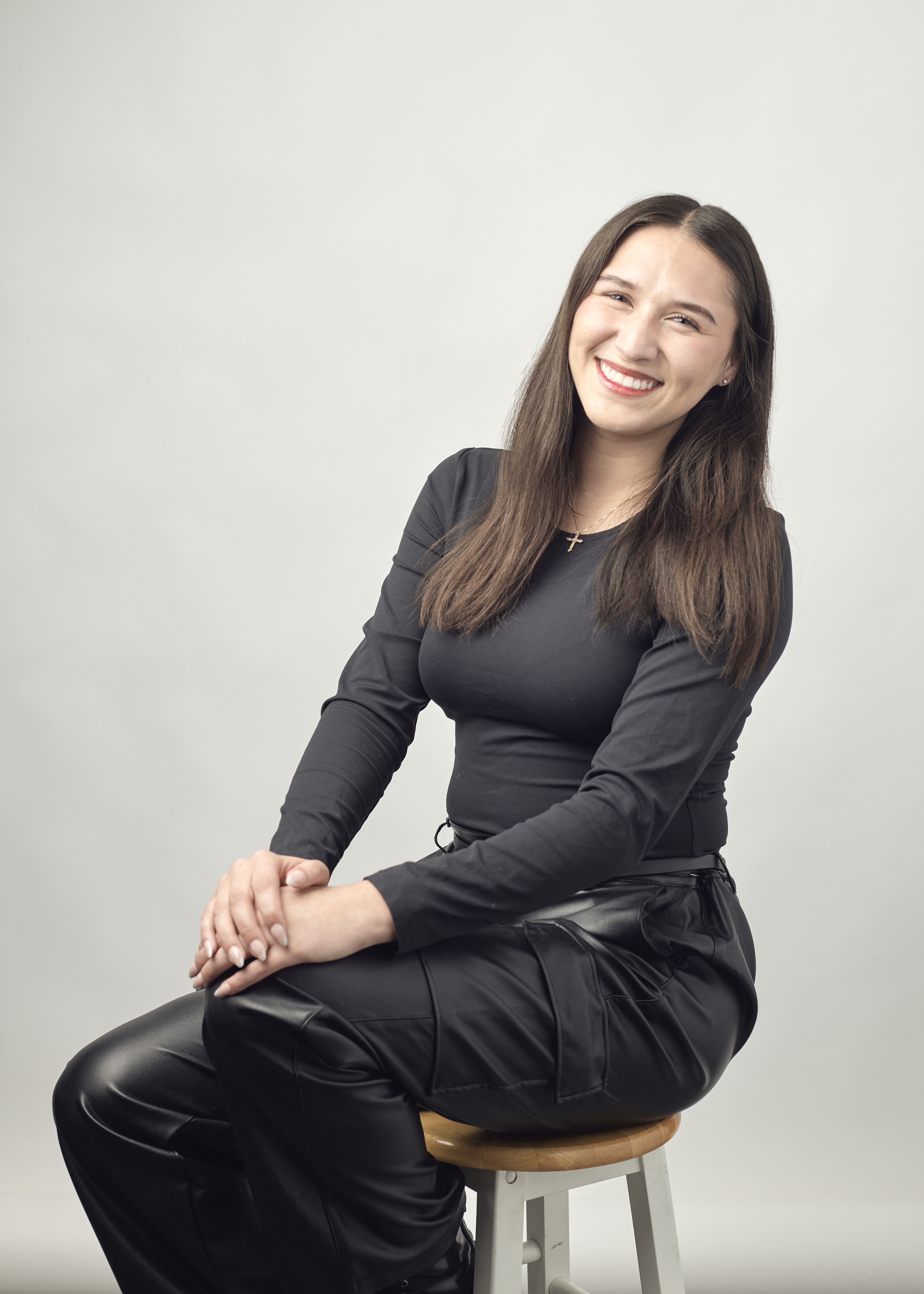 Maleeya is pictured, sitting on a stool and smiling.