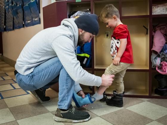 Patrick Pollock, a master's student in statistics, helps his son Luke Pollock, 2, switch his boots as they arrive at the ASMSU Early Learning Center on Thursday, Nov. 3, 2022, at Montana State University in Bozeman, Mont. MSU was recently awarded a Child Care Access Means Parents in School (CCAMPIS) grant to help support parent success in higher education. MSU Photo by Colter Peterson