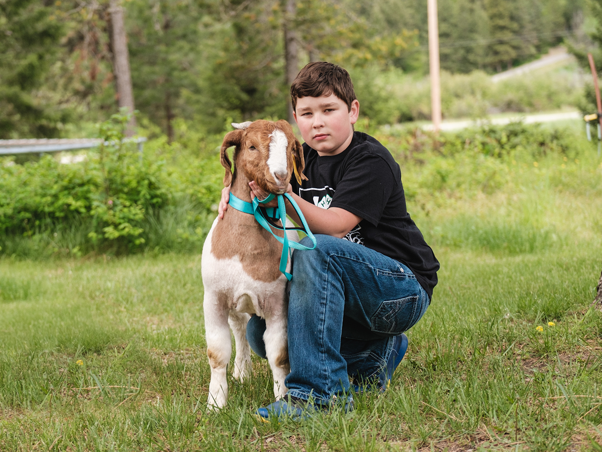 4-H member kneeling next to a goat