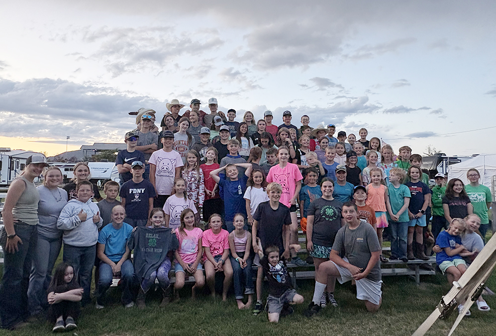 A group of kids on bleachers at the fair. 