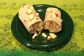 An apple wrap cut in half on a green plate.