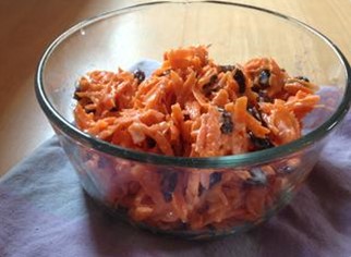 A glass bowl filled with carrot raisin salad. 