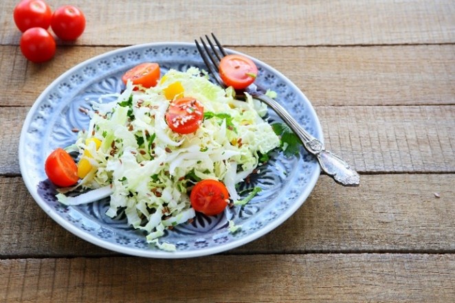 A plate of Crunchy Cabbage Salad topped with tomatoes.