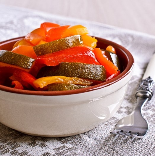 An image of summer bounty salad in a white bowl next to a fork.