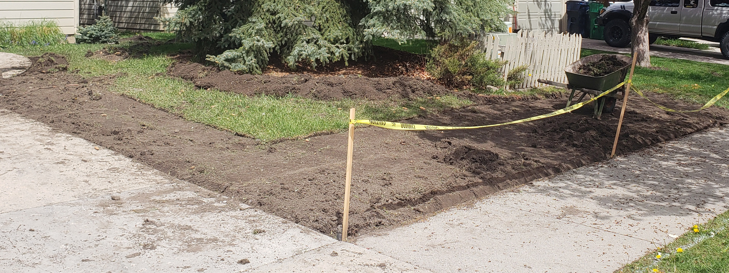 The outside lawn of a house, grass remains in patches as most of it was torn up neatly leaving dirt behind.