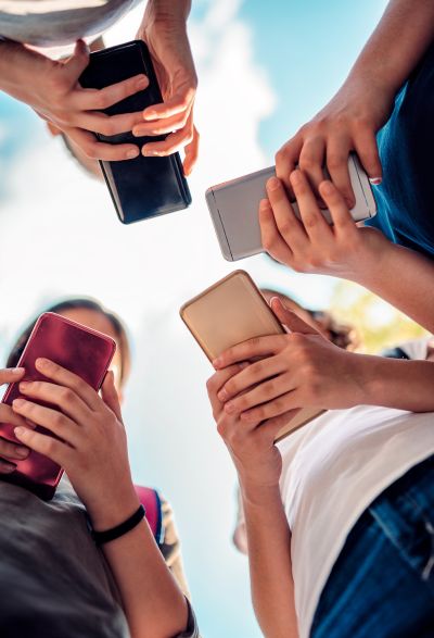 Several people holding smartphones and looking at their screens while standing outdoors.