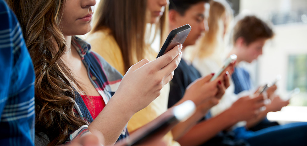 Group of young people using smartphones while seated together.