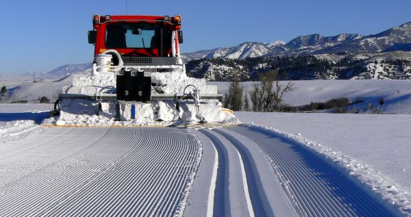 A machine grooms fresh nordic tracks in Highland Glen on a clear, sunny winter day.