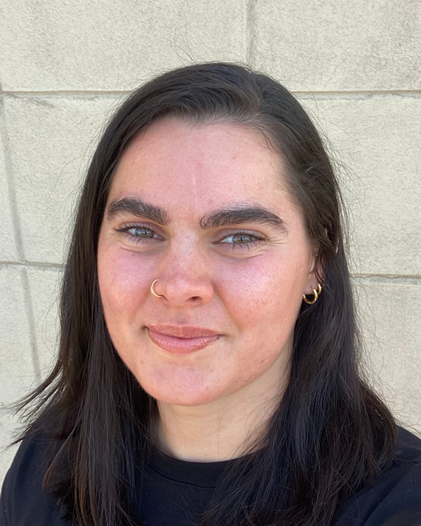 A person with long black hair with a hook nose ring wearing a black shirt