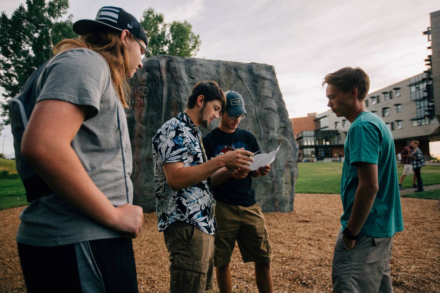 Students at climbing rock looking at paper