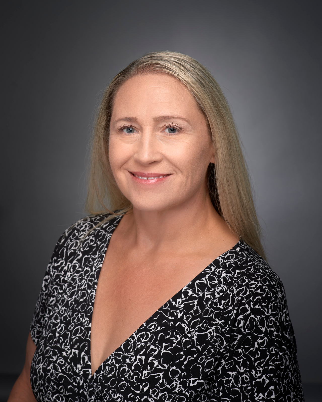 Portrait of a person with long blonde hair wearing a black shirt with a white pattern on it