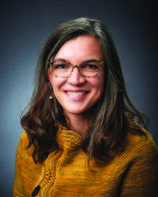 A headshot of a woman, Laura Goodell, M.D., with long dark hair and glasses, smiling and looking straight ahead. 